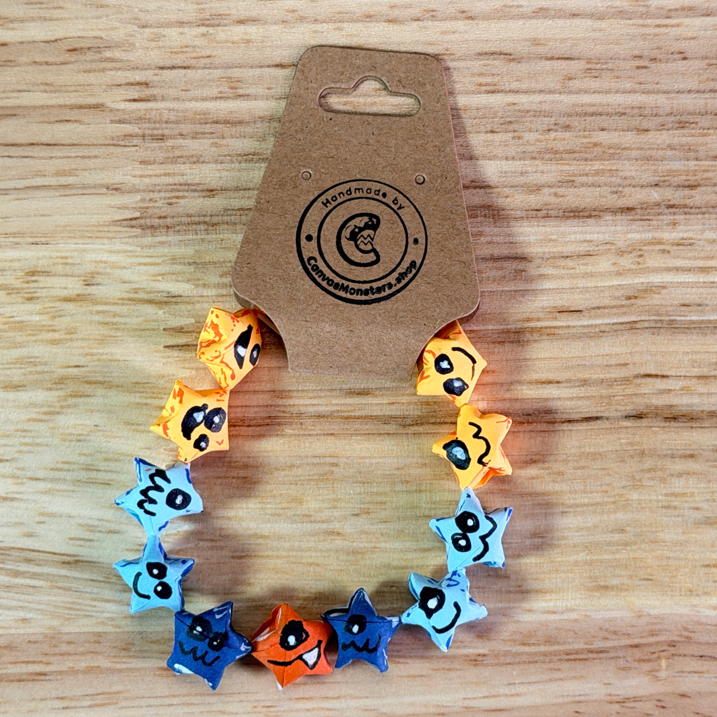 Bracelet with yellow, blue, and one orange paper origami star-shaped charms on a wooden background