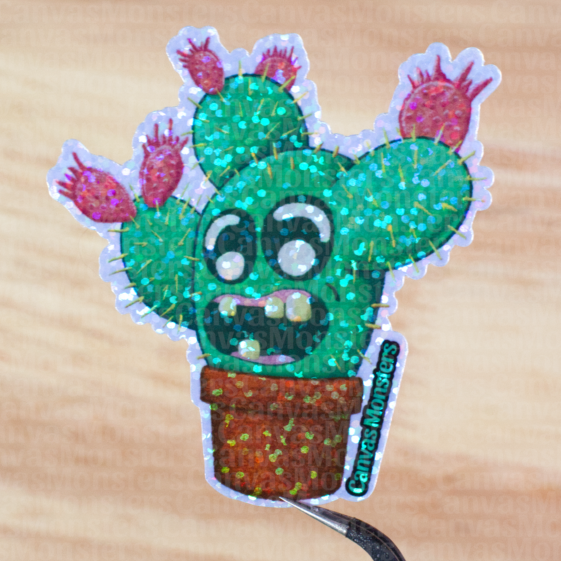 Glittery sticker of a cactus character with a happy grin being held above a wooden background