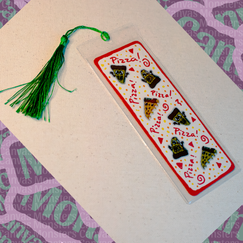 White paper bookmark with mini Canvas Monsters pizza stickers with a painted red border, in a plastic sleeve and green tassel.