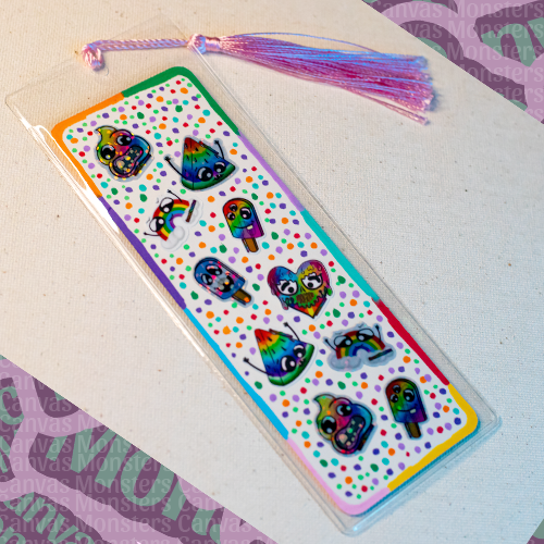 Colorful bookmark covered in mini Canvas Monsters Pride stickers on a white surface  in a clear plastic sleeve and a pink/purple tassel.
