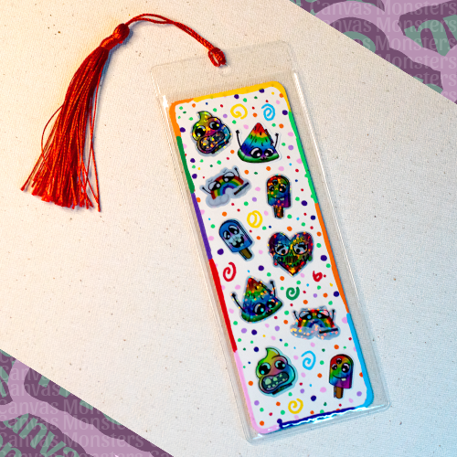 White paper bookmark with mini Canvas Monsters Pride stickers with a colorful painted background of swirls and dots, a colorful border, in a plastic sleeve and red tassel.