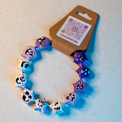 Bracelet with various shades of purple paper origami star-shaped charms on a beige background