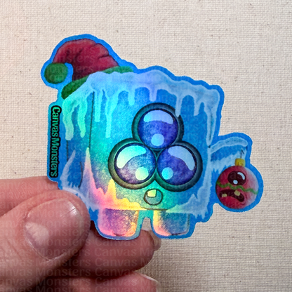 Holographic sticker of a cartoon ice cube held by a hand on a textured beige background