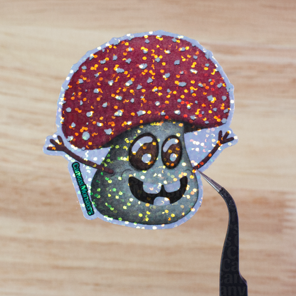 Glitter sticker of a cartoon mushroom held above a wooden surface