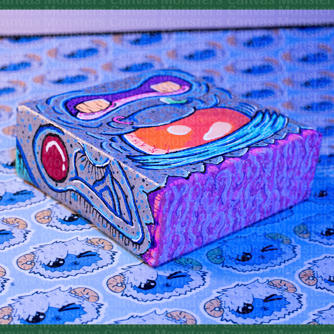 Colorful abstract Monster painting on a canvas block. Featuring a giant orange eye, blue skin, and silver highlights. 