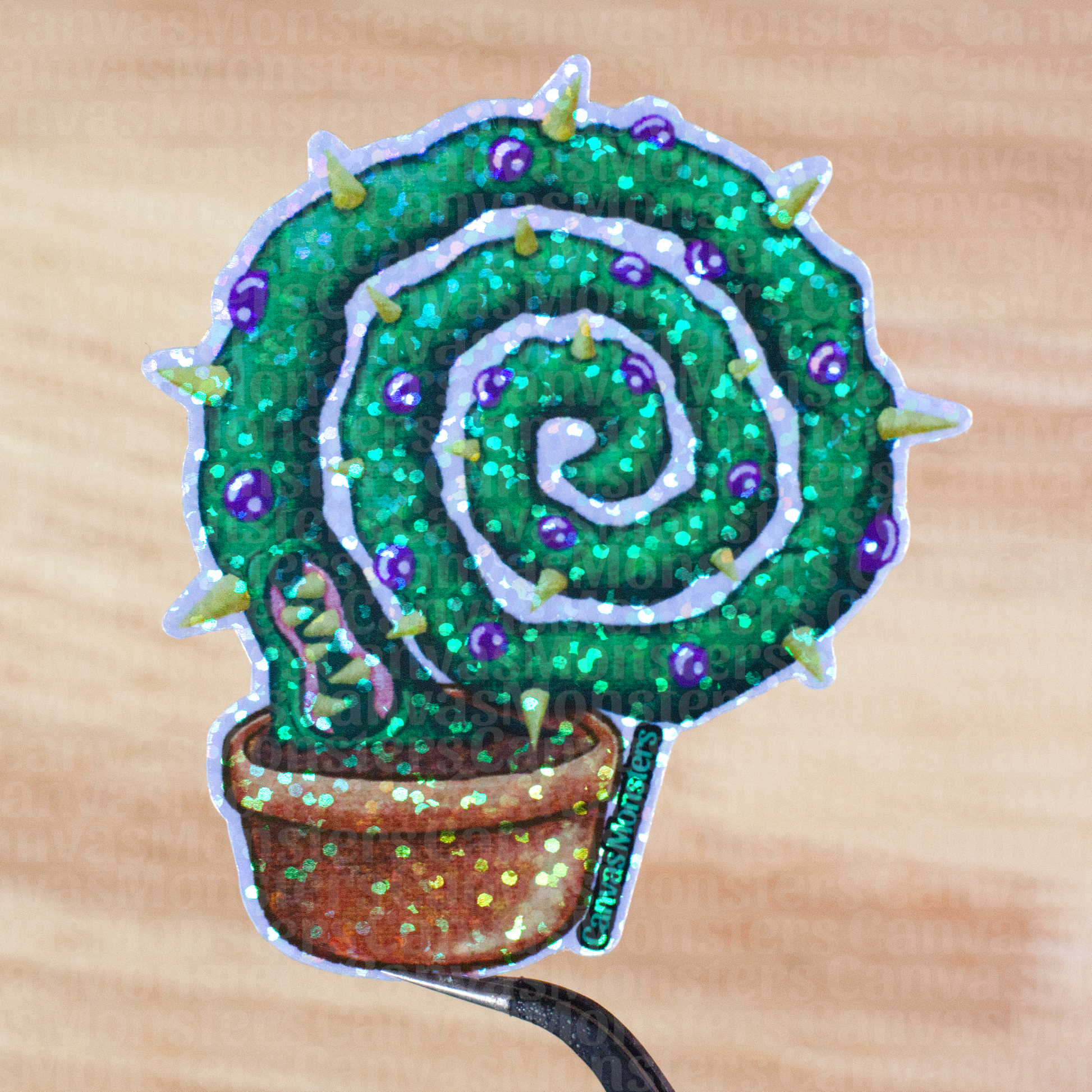 Glitter sticker of a spiral cactus character held above a wooden surface