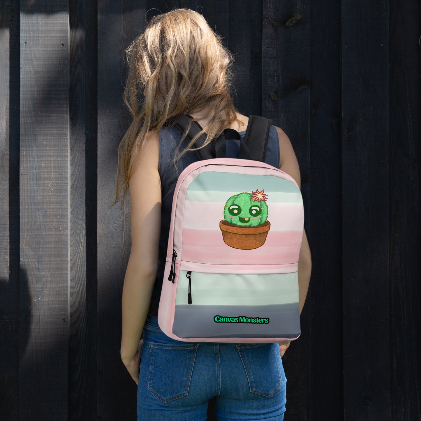 A woman viewed from behind wearing a pastel striped backpack with a cute cartoon cactus in a pot. The backpack features pink, light blue, and gray horizontal stripes, a gray bottom panel with a green 'Canvas Monsters' logo, and a front zippered pocket.
