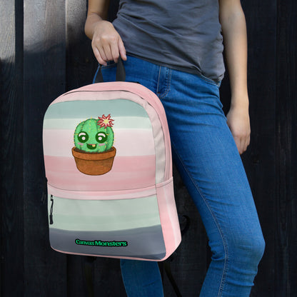 A person wearing a gray t-shirt and blue jeans carries a pastel striped backpack featuring a cute green cactus in a pot. The backpack has pink, light blue, and gray horizontal stripes with a small green 'Canvas Monsters' logo at the bottom.