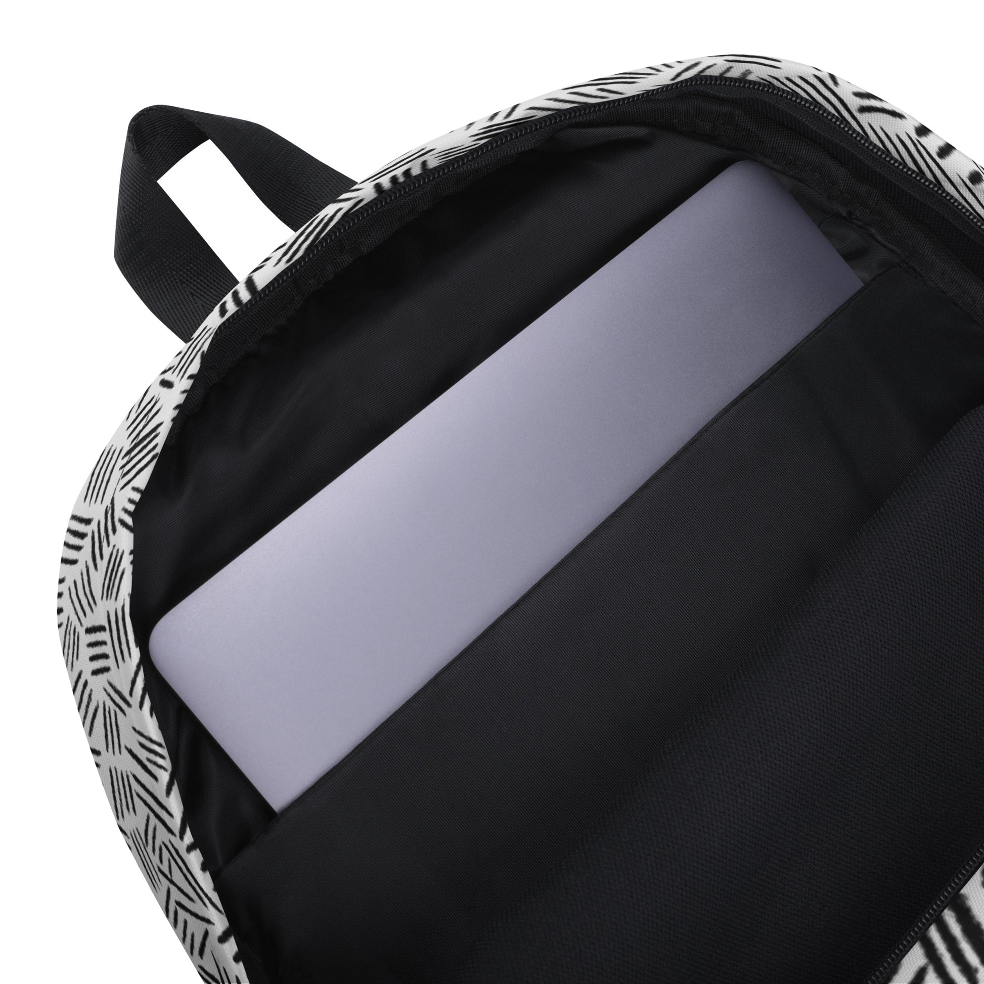 Close-up of the inside of a backpack with a black and white geometric patterned exterior, a black interior lining, and a light gray laptop inserted into a padded compartment.