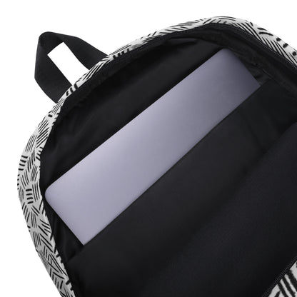 Close-up of the inside of a backpack with a black and white geometric patterned exterior, a black interior lining, and a light gray laptop inserted into a padded compartment.