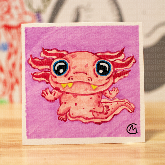 A square art print featuring a cute pink axolotl illustration on a pink background, standing on a wooden surface with a blurred background.