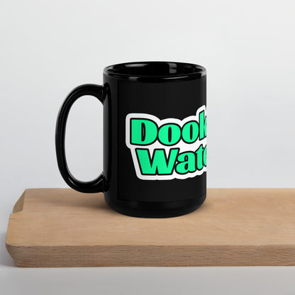 Black mug with green and white text on a wooden block against a white background