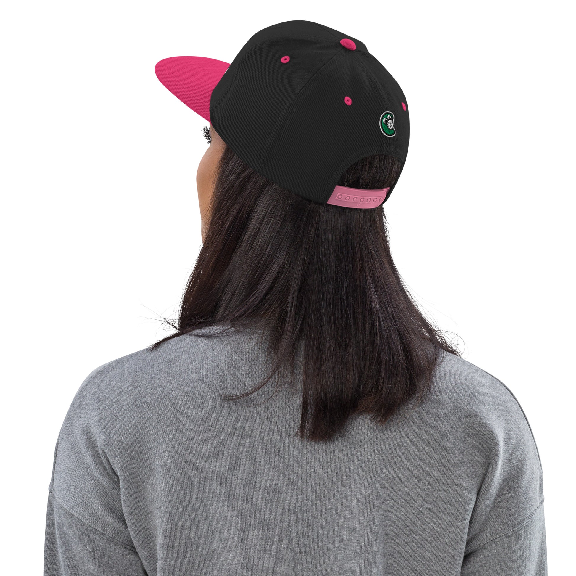 Person wearing a black and pink cap with a logo on a white background