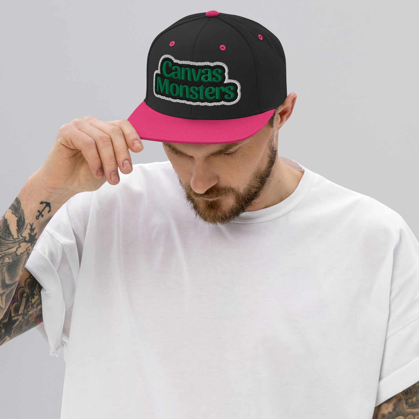 Man wearing a black and pink cap with 'Canvas Monsters' logo on a gray background