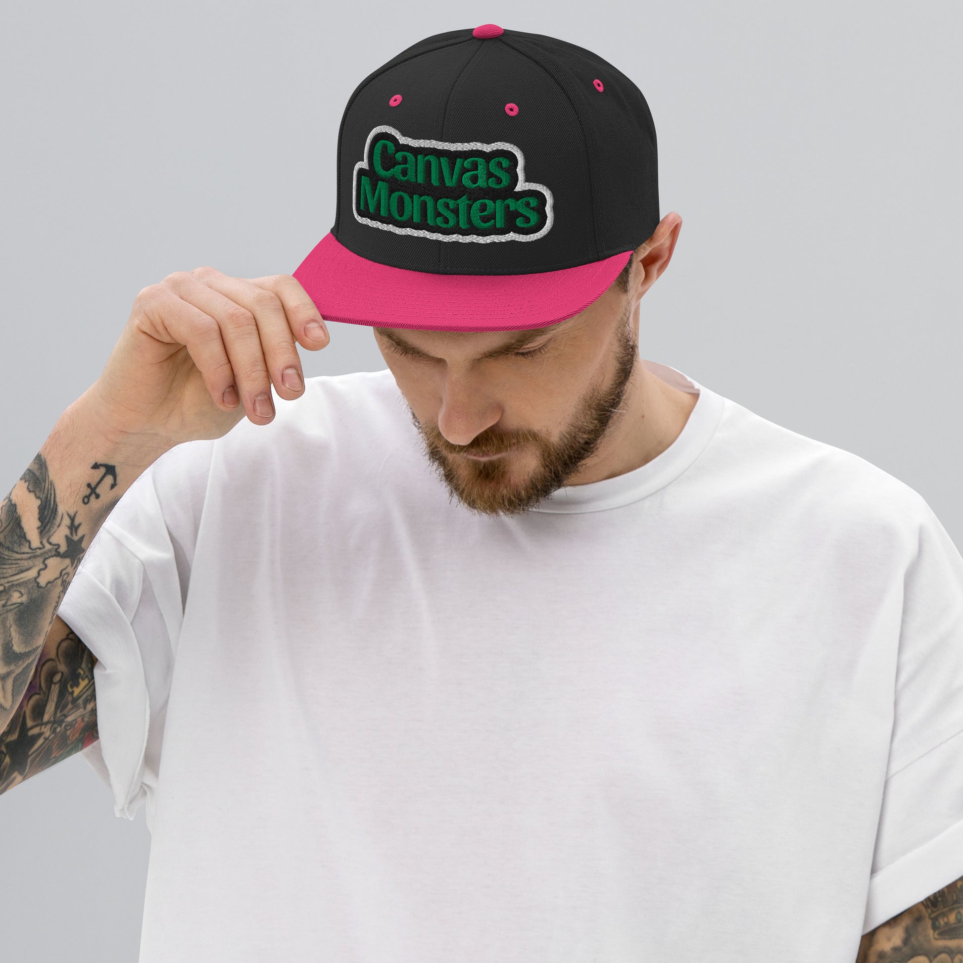 Man wearing a black and pink cap with 'Canvas Monsters' logo on a gray background