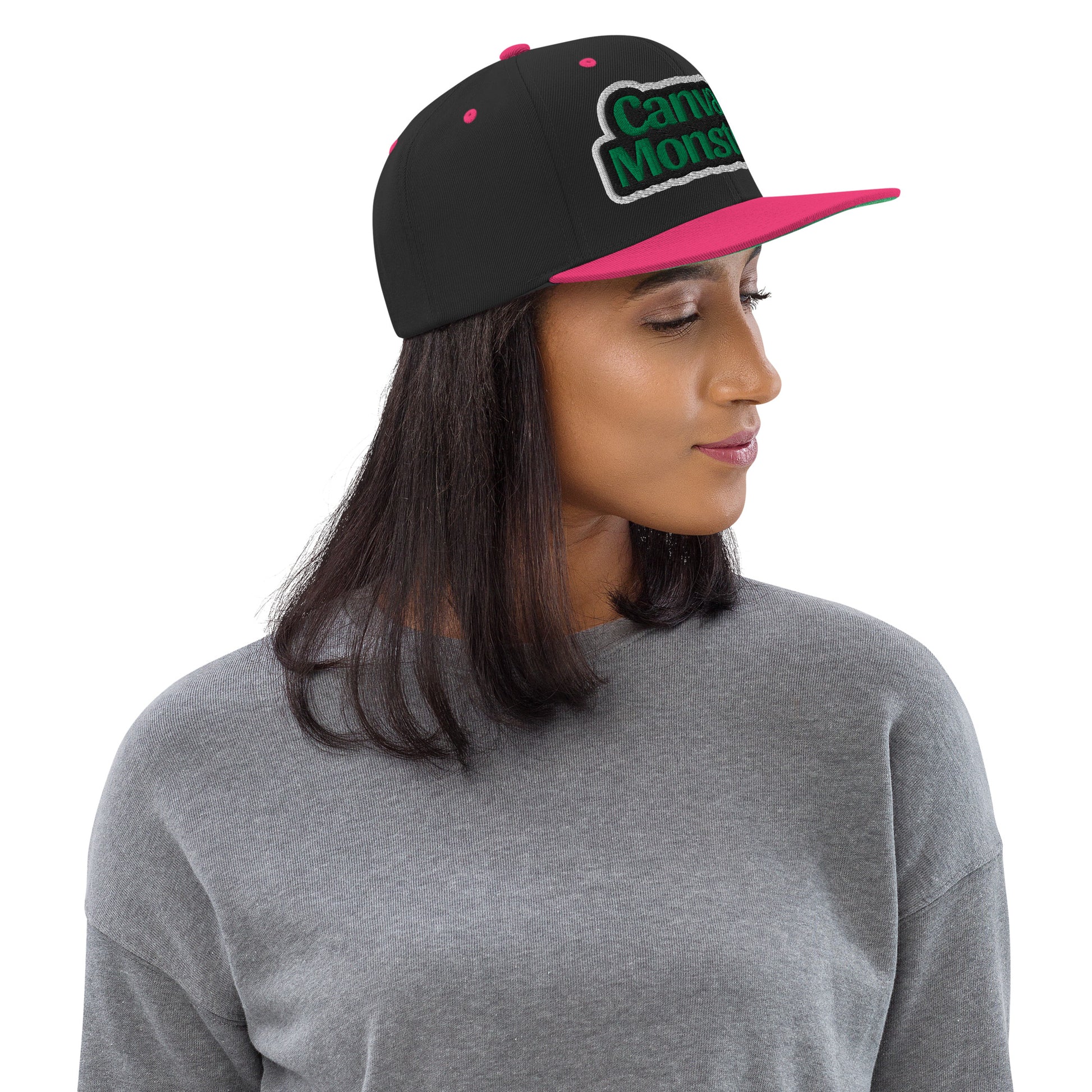 Person wearing a black and pink cap with 'Canvas Monsters' text on a white background