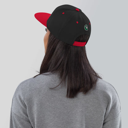 Person wearing a black and red cap with a logo on a plain background