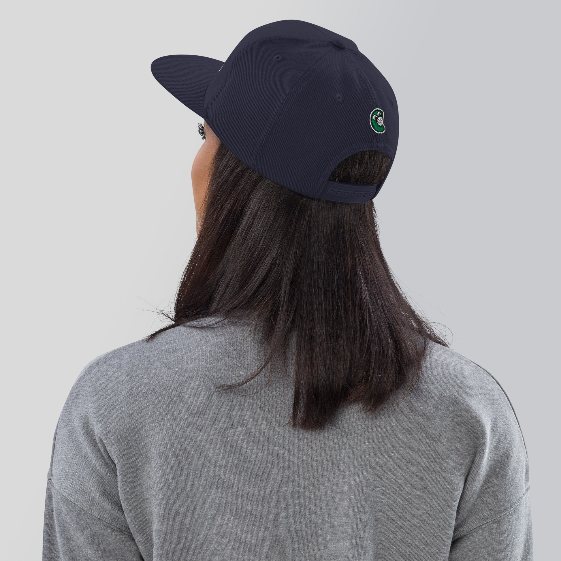 Person wearing a navy blue cap with a logo on the back, against a plain background
