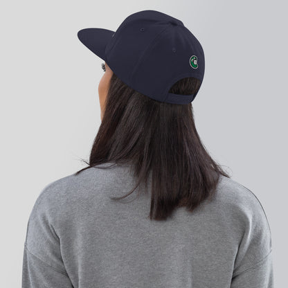 Person wearing a navy blue cap with a logo on the back, against a plain background