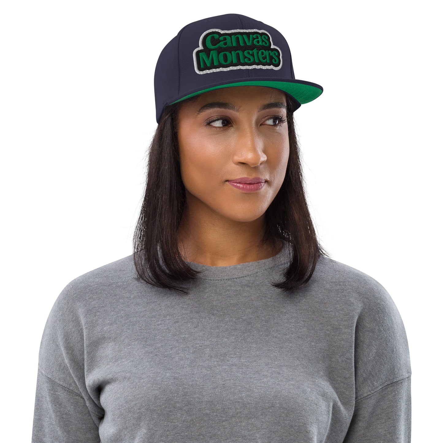 Woman wearing a navy cap with 'Canvas Monsters' logo on a white background