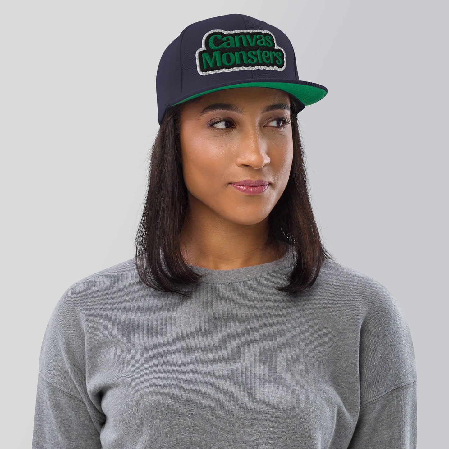 Person wearing a cap with 'Canvas Monsters' logo on a plain background
