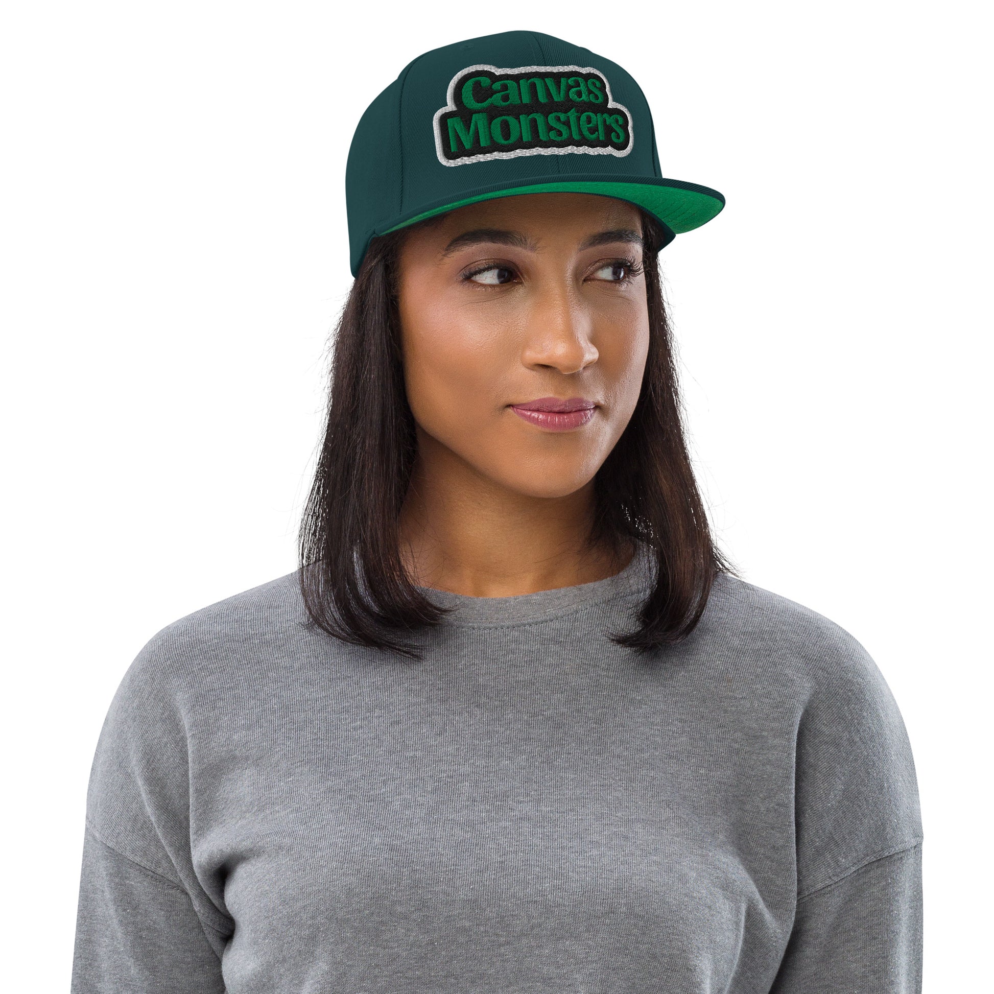 Woman wearing a green 'Canvas Monsters' cap on a white background