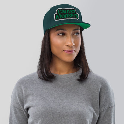 Person wearing a green 'Canvas Monsters' cap against a gray background