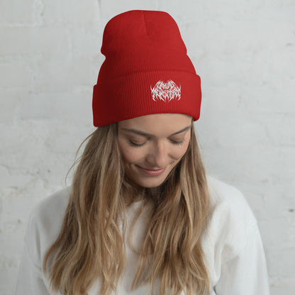 Woman with long blonde hair wearing a red knit beanie with a metal text logo on the front.