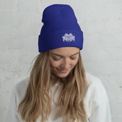 Woman with long blonde hair wearing a blue knit beanie with a metal text logo on the front.