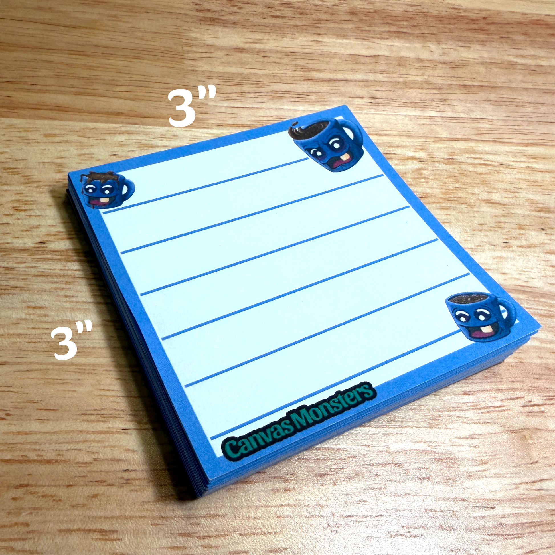 3x3 inch memo pad with a blue border and a coffee cup cartoon character in the corners, sitting on a wooden background.
