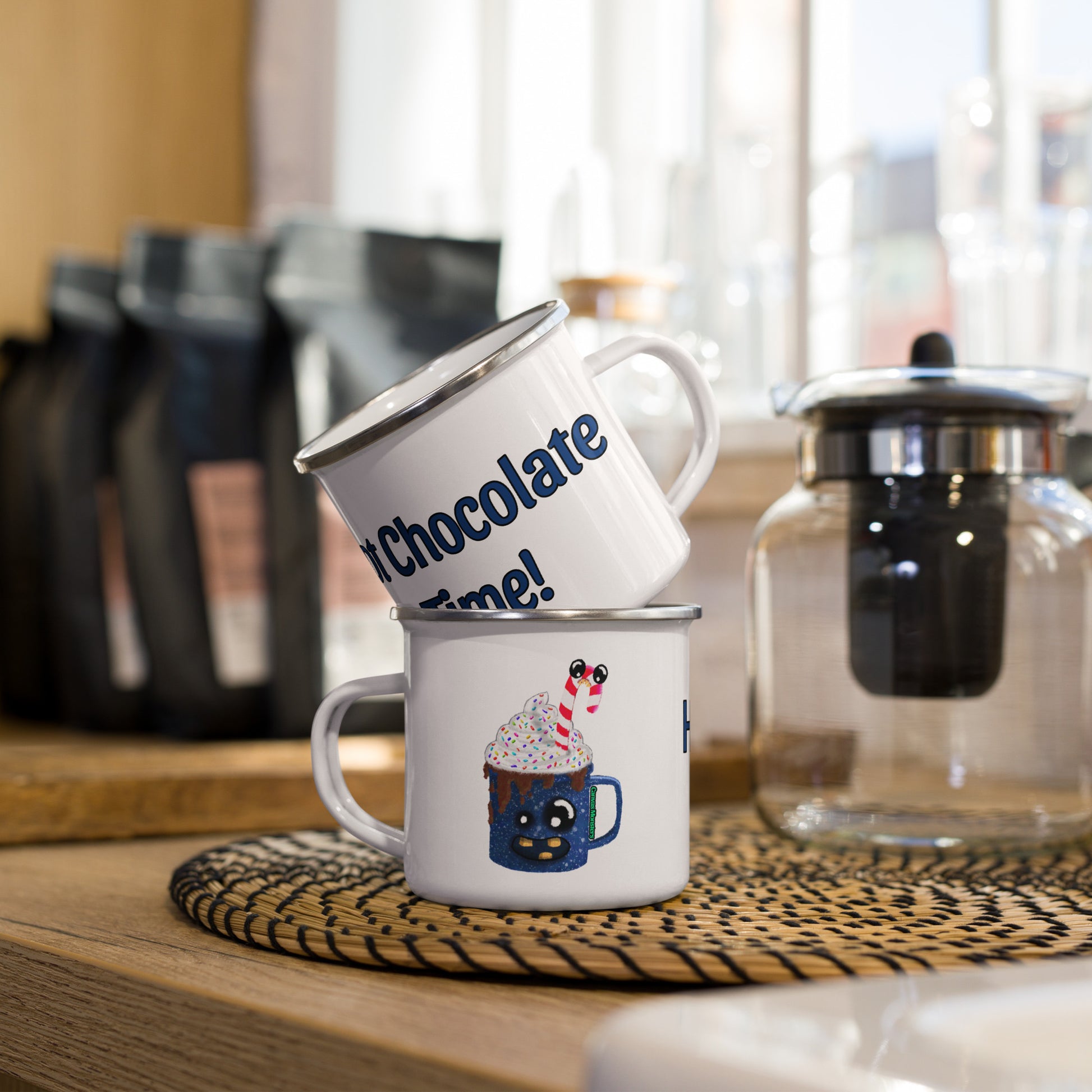 Two white enamel mugs stacked on a kitchen counter with coffee beans and a coffee maker in the background.