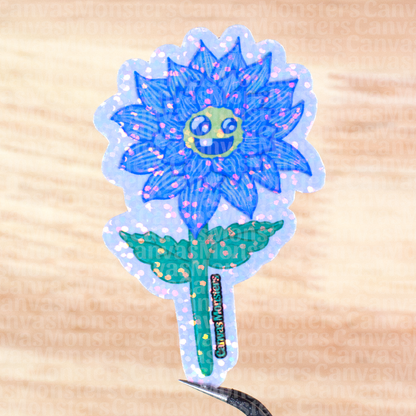 Glittery sticker of a blue flower with a smiling face on a wooden surface