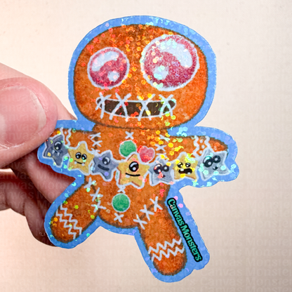 Glitter sticker of a gingerbread man-shaped cookie holding colorful star decorations on a textured beige background