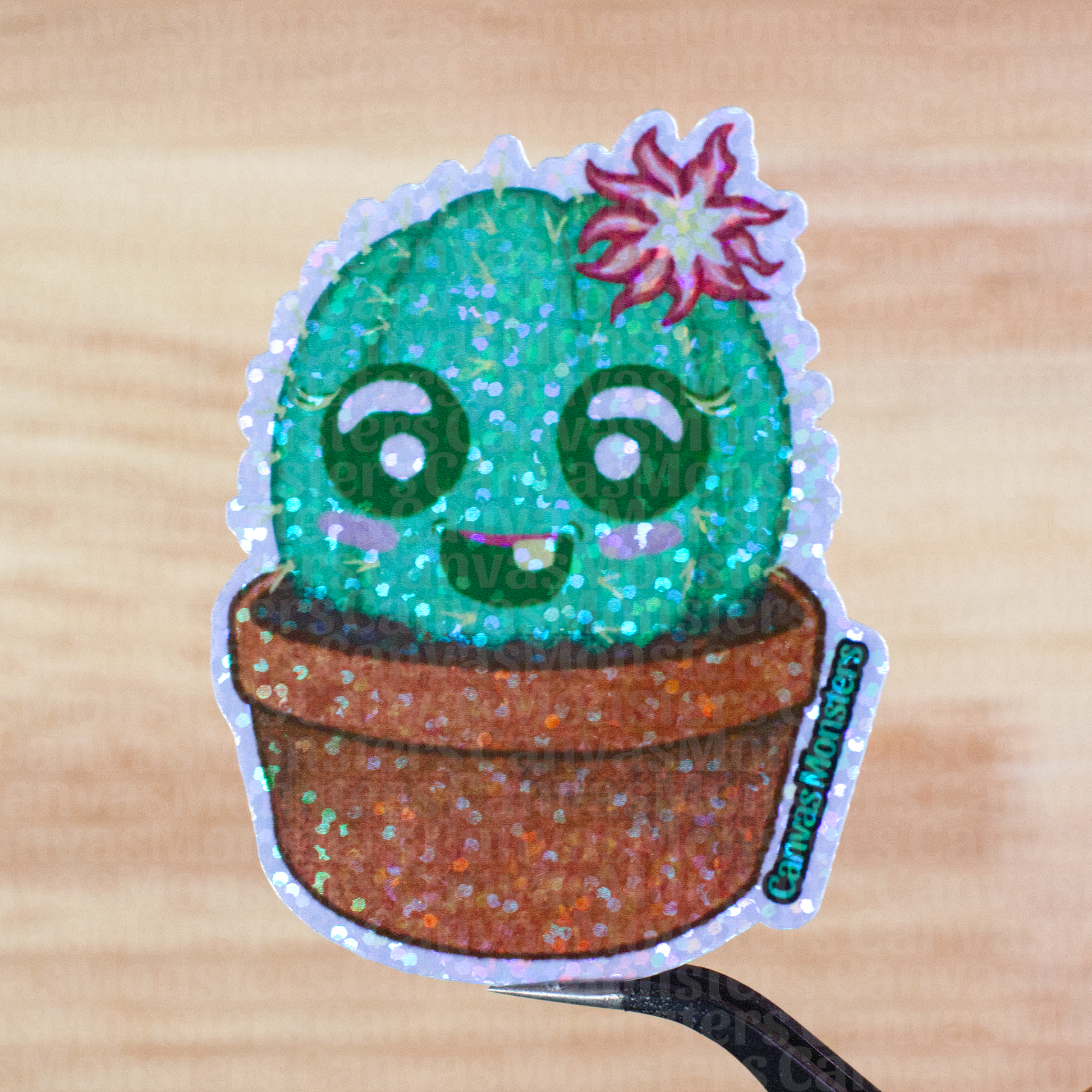 Glitter sticker of a cute cactus with a smiling face held above a wooden surface
