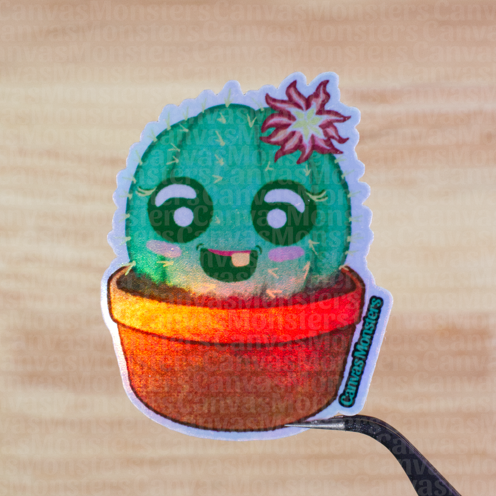Holofoil sticker of a cartoon cactus character with a flower held above a wooden surface