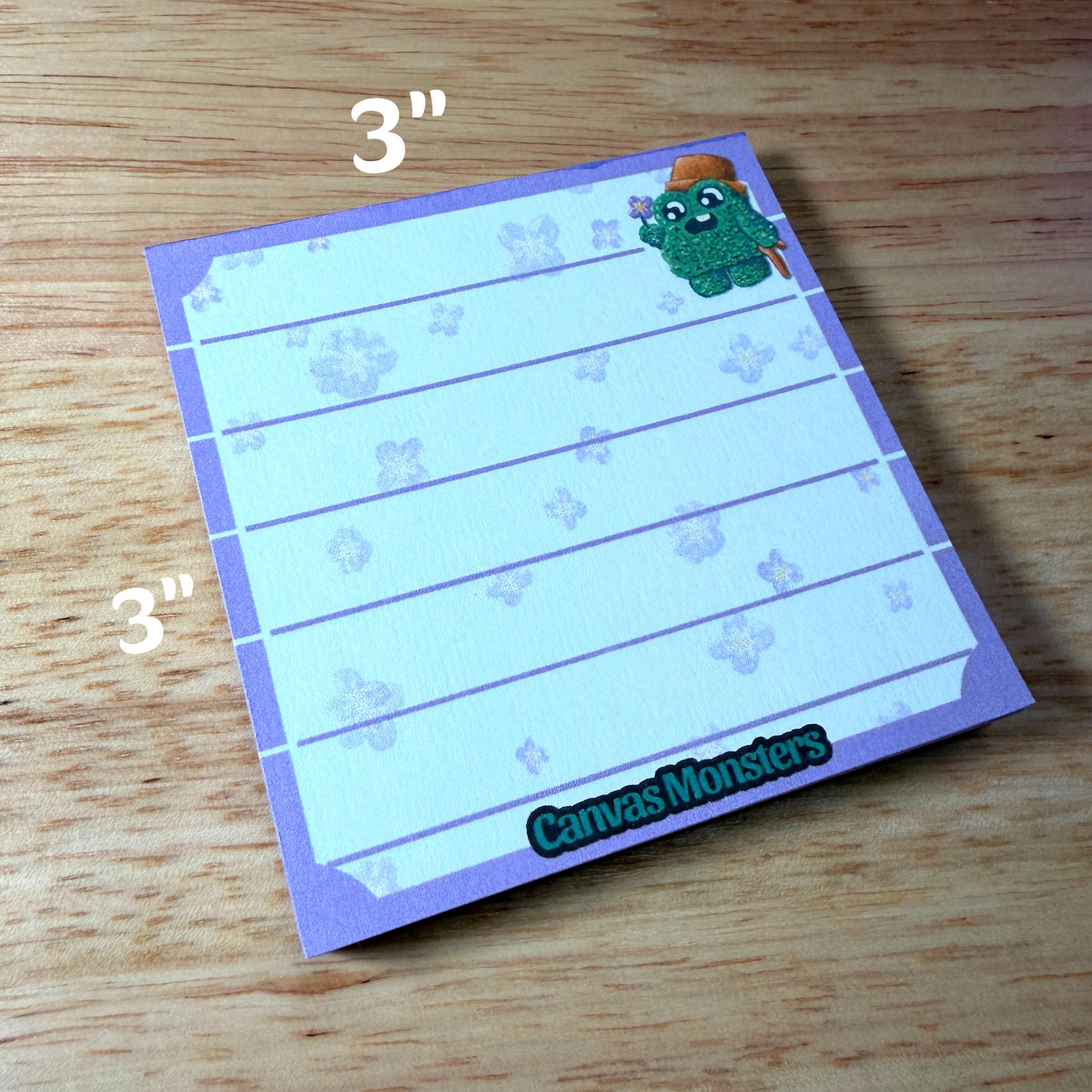 3x3 inch memo pad with a purple border and a shrub cartoon character in the top right corner, sitting on a wooden background.