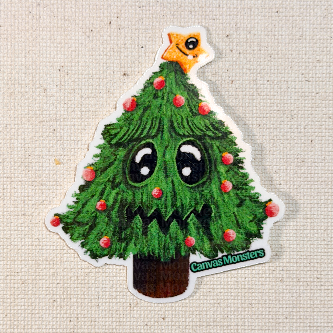Sticker of a cartoon Christmas tree with a star on top, eyes, and mouth, branded 'Canvas Monsters', on a textured beige background.