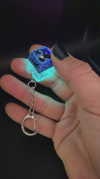 Video of a key cap keychain against a black background. Cap is painted with a blue monster character.
