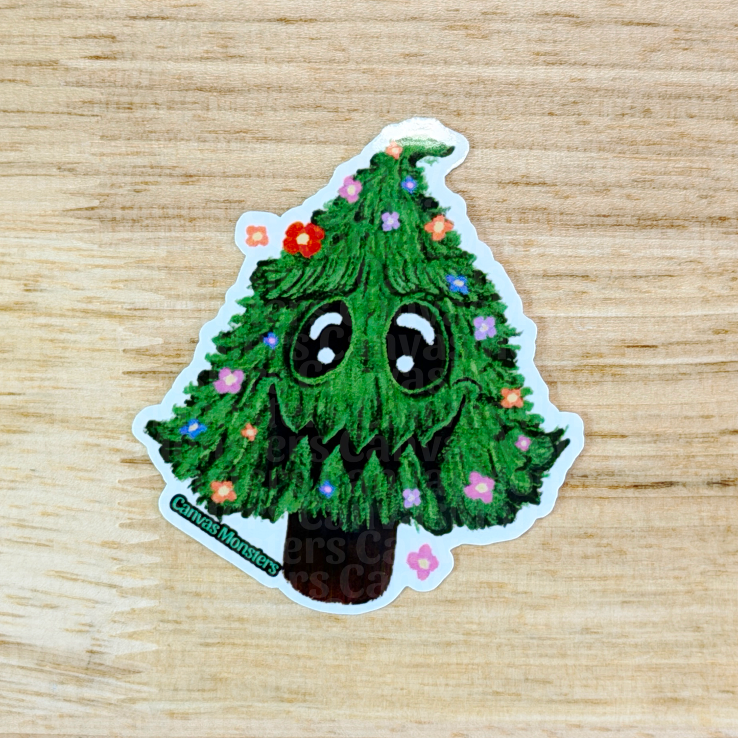Sticker of a green tree with facial features and flowers on a wooden surface